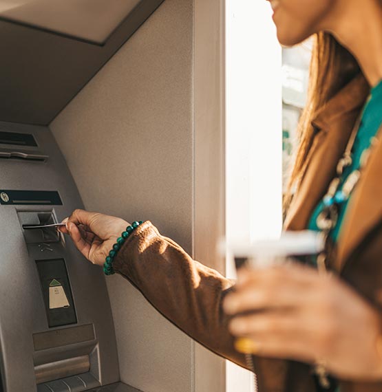 happy woman inserting card in ATM/ITM