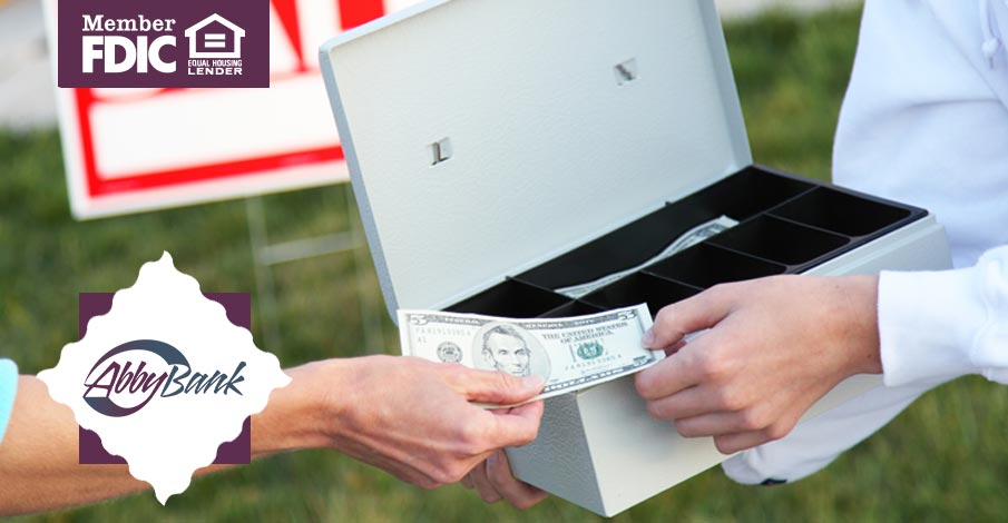 Person handing money to a person with a lock box for cash at garage sale