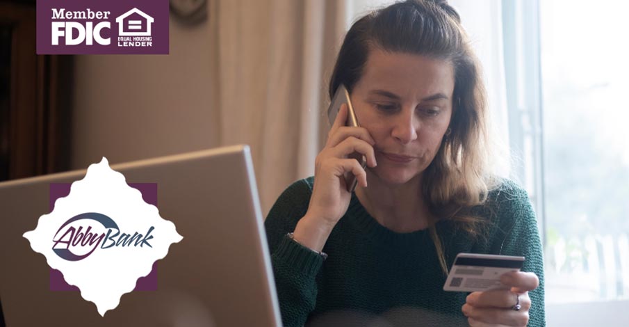 woman on laptop talking on cell phone while frowning looking at a card