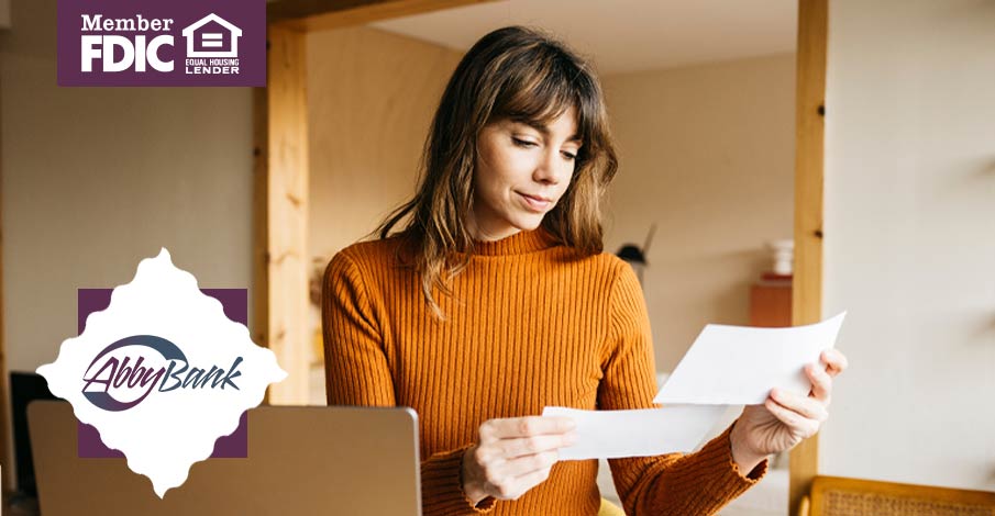 woman looking over papers with open laptop nearby