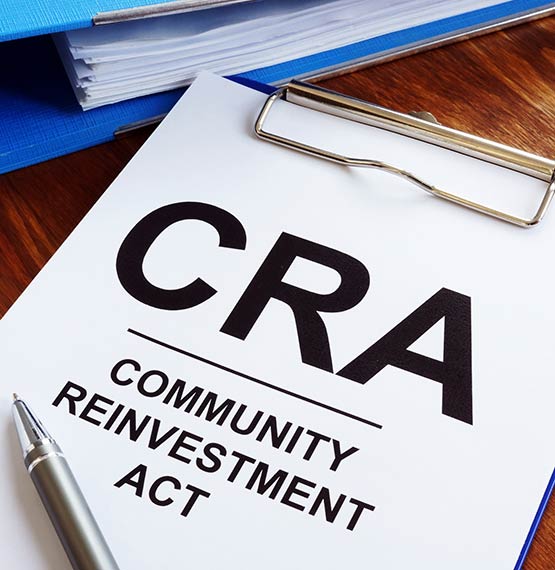 CRA Community Reinvestment Act wording on paper on blue clipboard