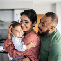 Mother and father embracing child in kitchen