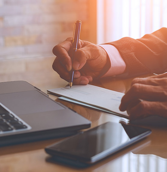 business man sitting at desk with laptop and writing out a business check