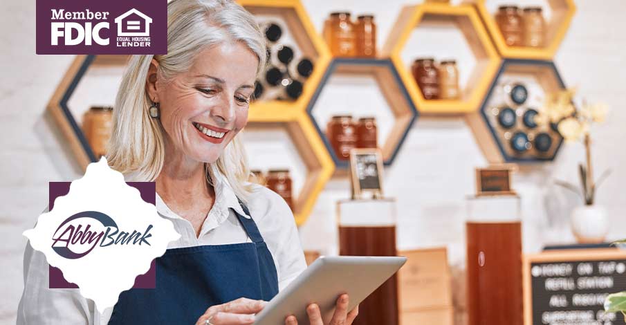woman business owner smiling looking at tablet while she's managing a store counter