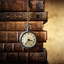 vintage watch on chain over background of old books