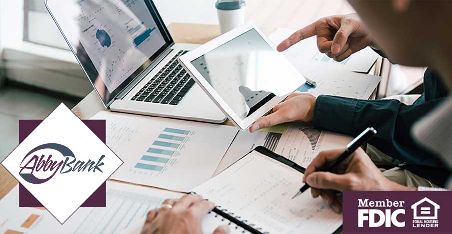 two people looking at laptop, tablet, and paperwork for banking