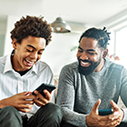 father and teen son smiling looking at phones