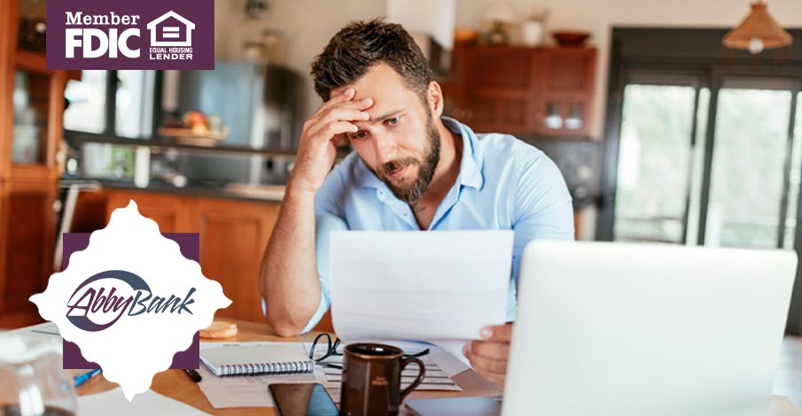 man looking at paperwork and open laptop on island
