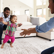 young parents encouraging baby's first steps