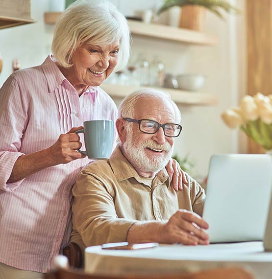 elderly couple smiling looking at laptop 