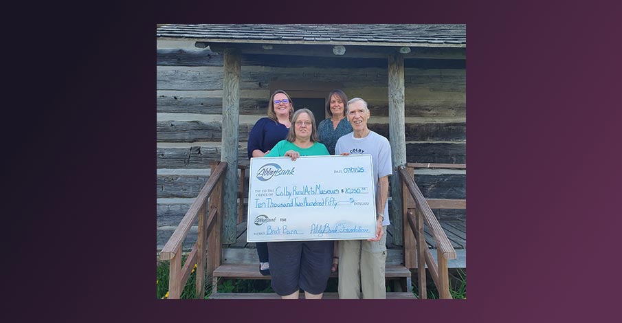 Karla and Hillary with AbbyBank posing with two members of Colby Rural Arts Museum holding a large check showing the special request donation from the AbbyBank Foundation for a new brat barn for the museum and community