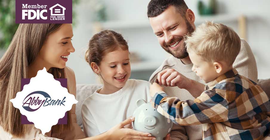 young family teaching their two kids about saving money in piggy bank