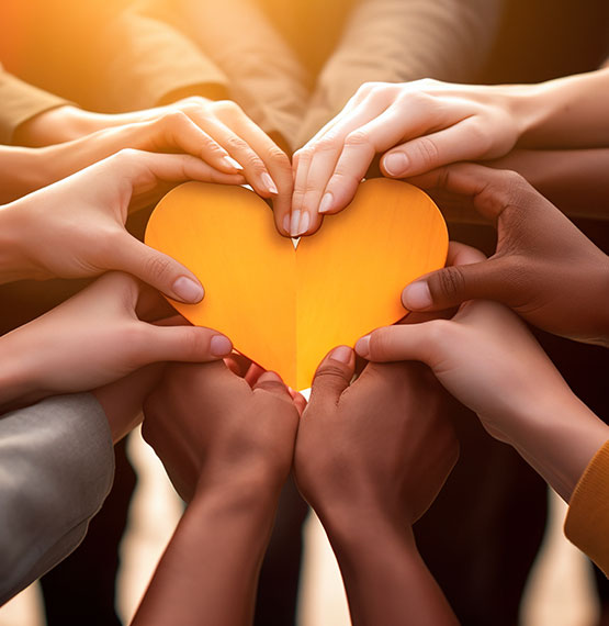 group of hands joined together holding a heart 