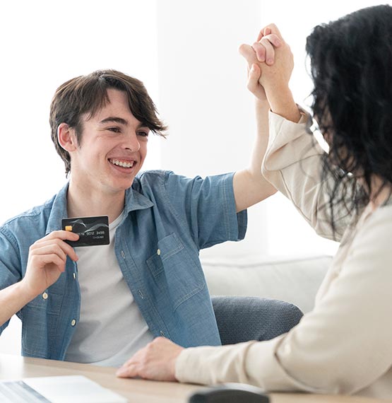 happy teen boy holding up debitcard and high-fiving his mom