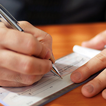 close up of a person's hands writing out a check