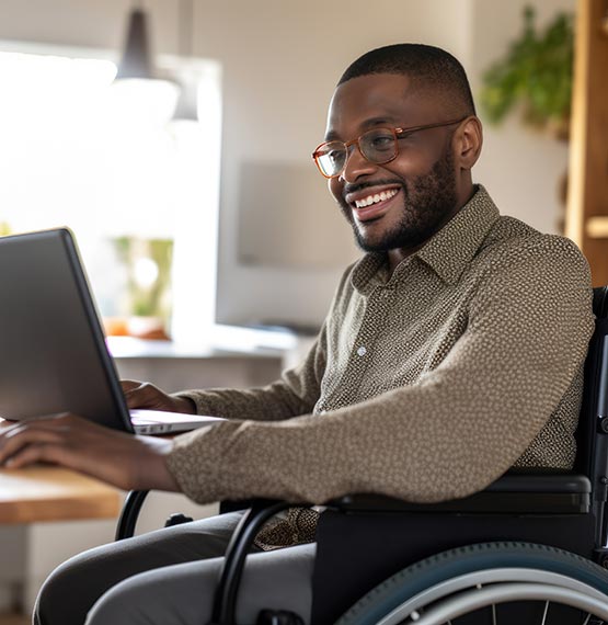 man in wheelchair working on laptop in office