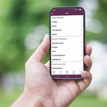 hand holding a mobile phone showing the "More" Screen in AbbyBank's personal Mobile Banking app