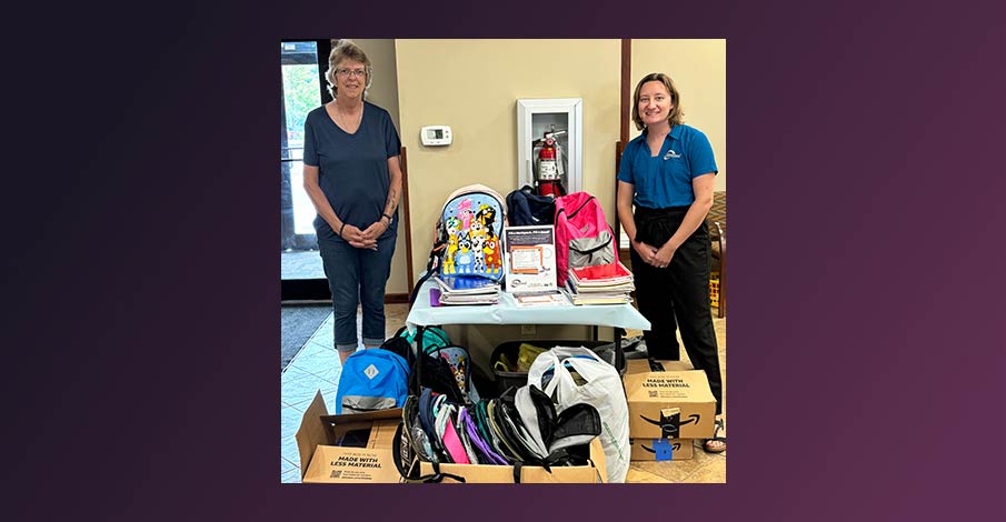 Kris Belanger with Peace Lutheran Church and Gail Leader, Marketing Coordinator at AbbyBank pose with a large collection of backpacks and other school supplies in Abbotsford AbbyBank 